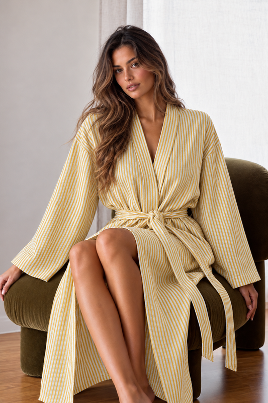Woman wearing the Marigold Stripe Cotton Kimono Robe, a mustard yellow and white striped cotton wrap robe with wide sleeves and a soft waist tie.