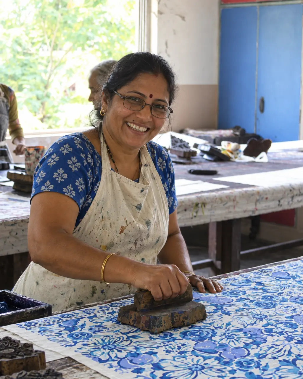 An artisan placing a carved wooden block onto fabric by hand