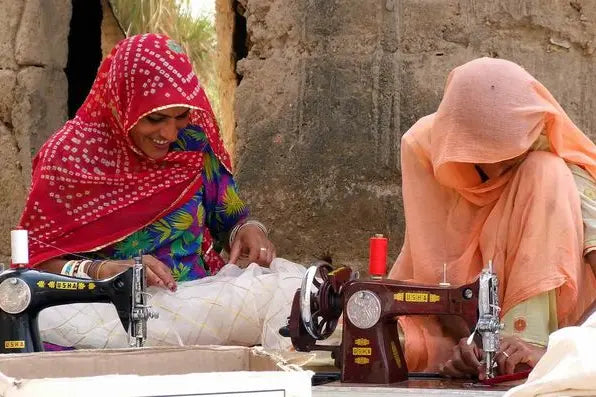 Women cutting and stitching printed cloth into garments