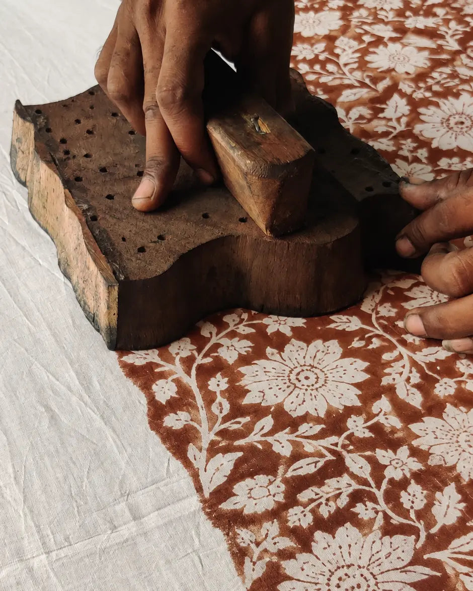 A carved wooden printing block held against printed cotton